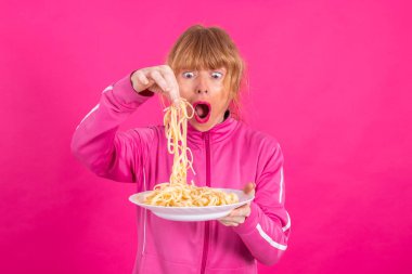 adult woman with plate of pasta and sportswear isolated on color background