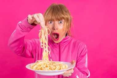 adult woman with plate of pasta and sportswear isolated on color background