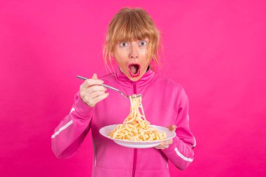 adult woman with plate of pasta and sportswear isolated on color background