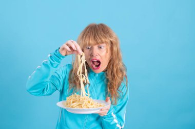 adult woman with sportswear and plate of pasta or spaghetti isolated on blue background