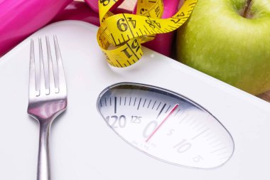 scale with measuring tape and fruit, diet and weight loss concept