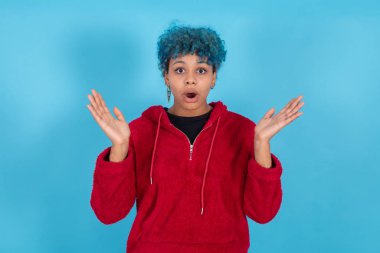 young woman or afro american girl isolated on blue background with expression