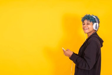 Cep telefonu ve kulaklığı olan genç bir kadın ya da kız. Renkli arka planda izole edilmiş. Mesaj ya da reklamlar için yeri var.