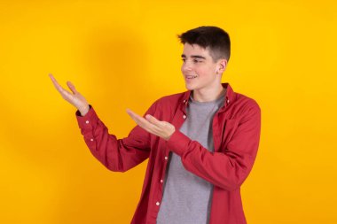 young teenager boy with shirt and casual shirt isolated on yellow background