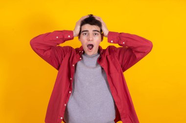 young man or teenage student with astonishment or surprise expression isolated on yellow background
