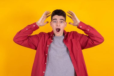 young man or teenage student with astonishment or surprise expression isolated on yellow background