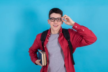 young teenage student with glasses backpack and books isolated on color background smiling