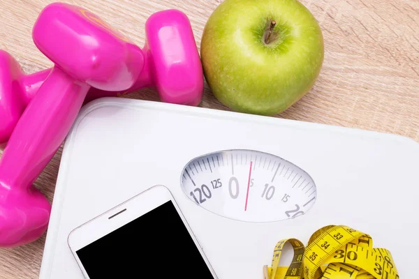 scales with fruit weights and mobile phone with measuring tape