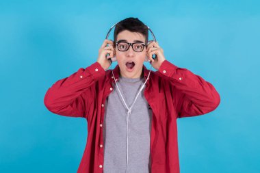 Renkli arka planda telefon ve kulaklıkları olan modaya uygun bir genç.