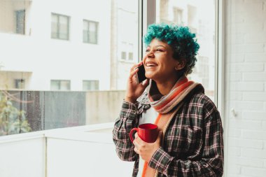 Evde ya da dairede fincanla konuşan genç bir kız.