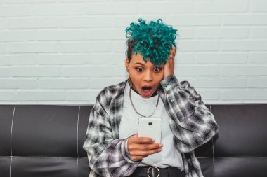 Kız cep telefonuna şaşkınlık ya da şaşkınlık ifadesiyle bakıyor.