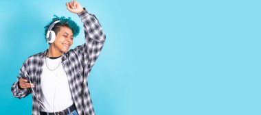 Mavi arka planda dans eden cep telefonu ve kulaklıklı esmer genç kız.