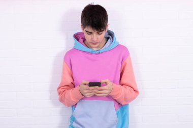 Cep telefonlu genç öğrenci beyaz tuğla arka planda izole