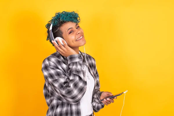 年轻的黑发女孩 带着手机和耳机 背景是彩色的 — 图库照片