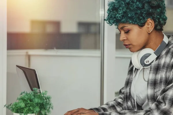 young afro american girl with headphones working on the computer