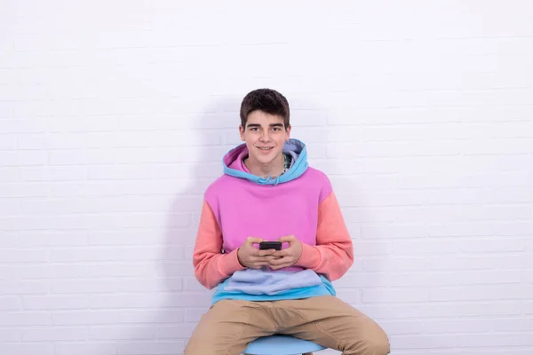 若い10代の男の子か携帯電話を椅子に座っている学生 — ストック写真