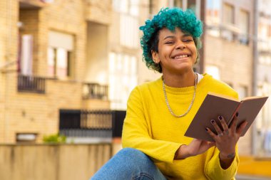 Açık havada kitabı olan Afro-Amerikalı genç bir kız.