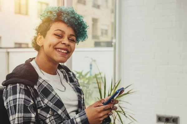 young woman or girl with mobile phone sitting at home or apartment