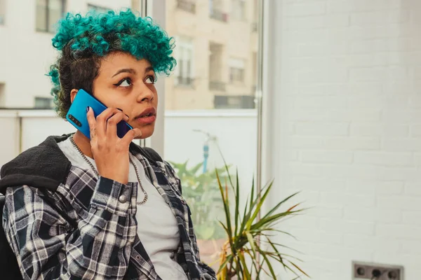 young woman or girl with mobile phone sitting at home or apartment