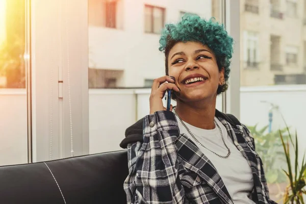 young woman or girl with mobile phone sitting at home or apartment