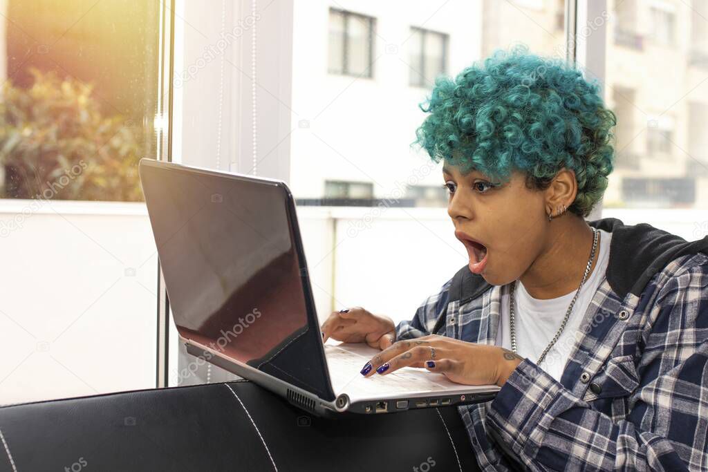 african american brunette girl looking at laptop screen with expression of surprise or admiration