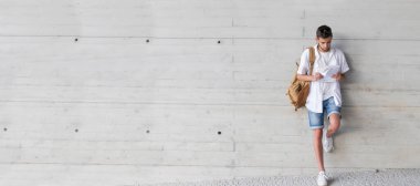 Dışarıda duvarda kitap ve sırt çantası olan bir öğrenci.