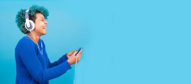 Renkli arka planda izole edilmiş cep telefonu ve kulaklıklı kız
