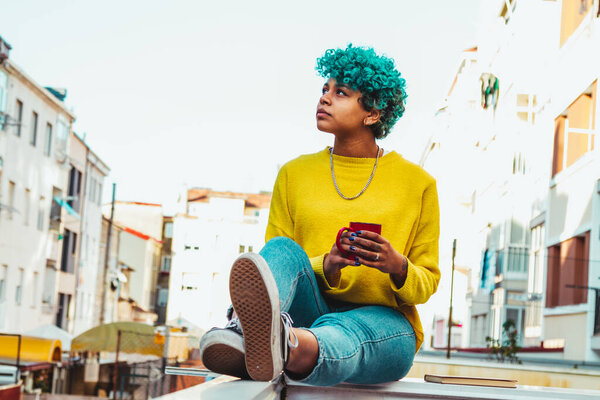 современная молодая девушка с чашкой кофе в городе на открытом воздухе
