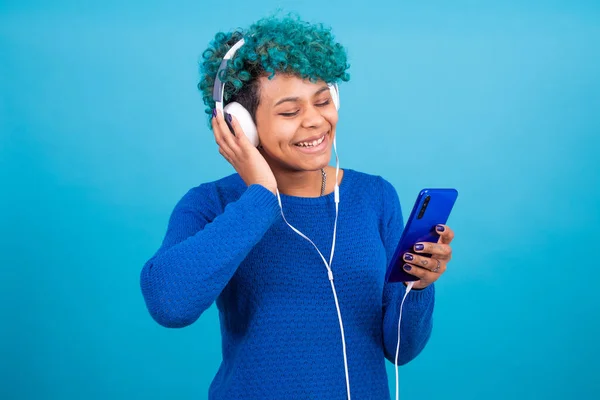 young girl with mobile phone and headphones isolated on color background