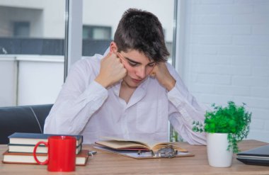 Masada ders çalışan genç bir öğrenci var.