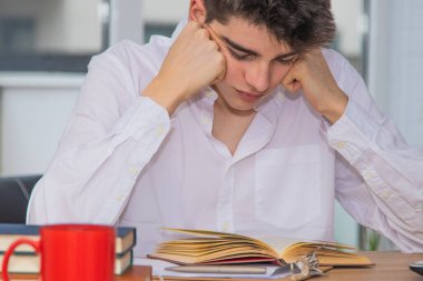 Masada ders çalışan genç bir öğrenci var.