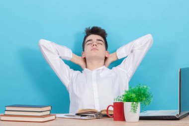 Rahatlama ifadesi olan öğrenci masada oturuyor.