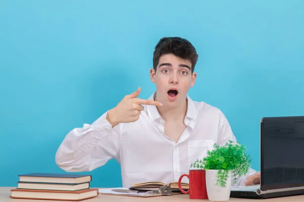 young student at the desk with computer and books and expression of surprise or admiration