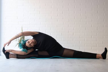 Sporcu kadın jimnastik yapıyor ya da evde ya da spor salonunda esniyor.