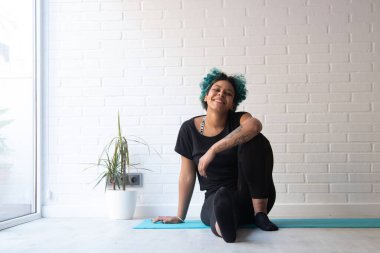 Sporcu kadın jimnastik yapıyor ya da evde ya da spor salonunda esniyor.