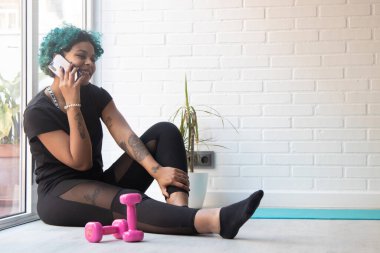 kız ya da kadın evde ya da spor salonunda cep telefonuyla spor yapıyor.