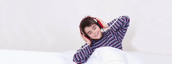 Menino Cama Sorrindo Ouvindo Música Com Fones Ouvido Fundo Branco — Fotografia de Stock