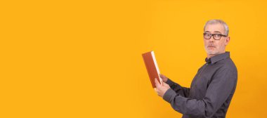 Kitabı renkli arkaplanda olan yetişkin ya da yaşlı adam