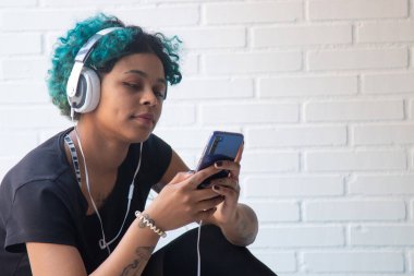 Cep telefonu ve kulaklığı olan müzik dinleyen genç bir kadının portresi.