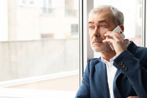 Pencerenin Önünde Cep Telefonuyla Konuşan Yetişkin Yaşlı Bir Adamın Portresi — Stok fotoğraf