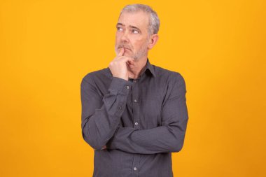 Yetişkin adam, düşünceli bir ifadeyle renk arkaplanında izole edilmiş.