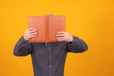 Yüzünü kapatan kitap ya da ajandası olan izole bir yetişkin adam.