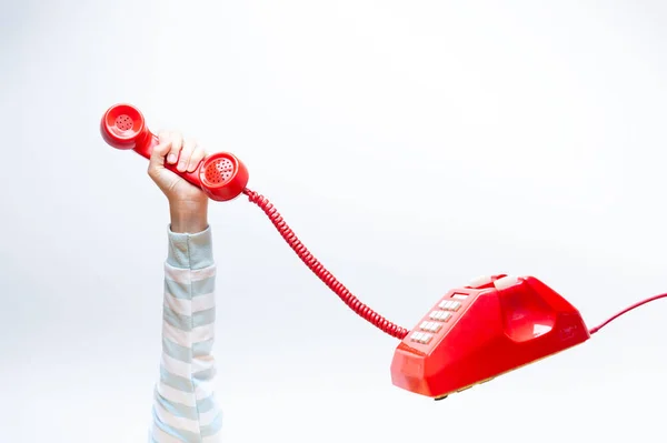 Mão segurando telefone vermelho — Fotografia de Stock
