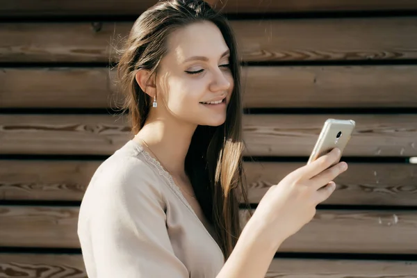 Chica con una cara juguetona, mira en el teléfono — Foto de Stock