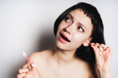 Kız kulakları pamuk tomurcukları ile temizler.