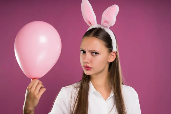 Een meisje met de oren van het konijn houdt een opblaasbare bal — Stockfoto