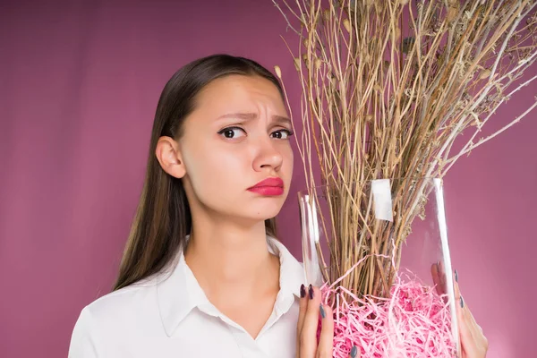 Una chica frustrada sostiene una planta seca en sus manos — Foto de Stock