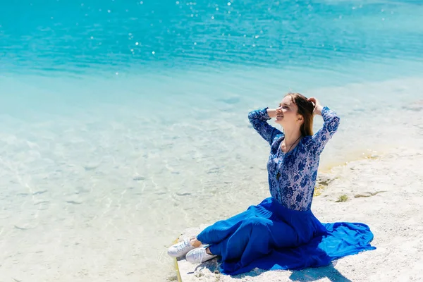 Mavi elbiseli bir kız gölde oturuyor