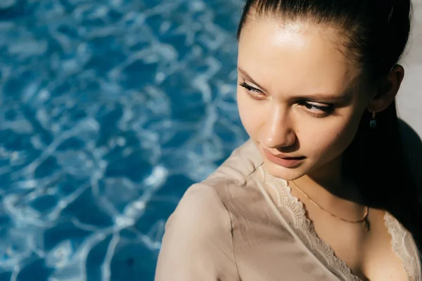 Bella ragazza sullo sfondo della piscina guarda da qualche parte — Foto Stock