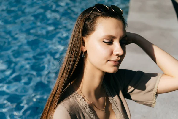 Mooi meisje op de achtergrond van het zwembad gesloten haar ogen — Stockfoto